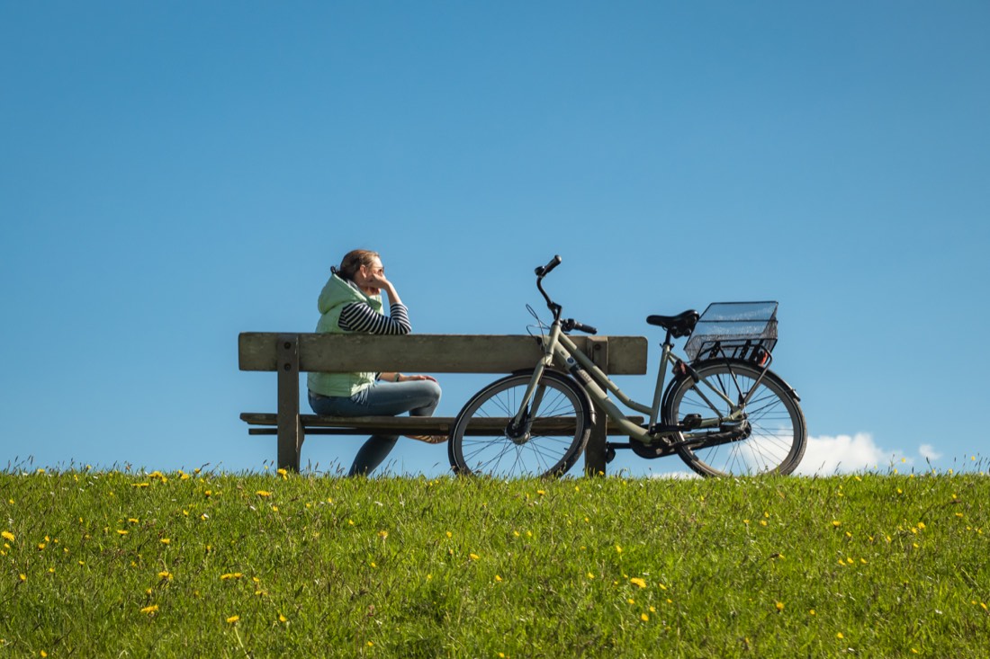 Frau macht mit ihrem Fahrrad eine Pause auf Pellworm
